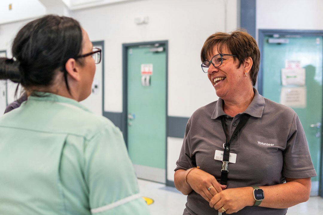 A Japanese female staff member talking warmly with an elderly visitor at reception